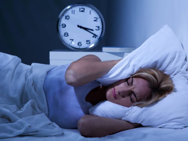 Budzik i bezsenna kobieta. Obrazek w artykule Cudowny sposób na bezsenność: 5 skutecznych metod, które pomogą Ci zasnąć