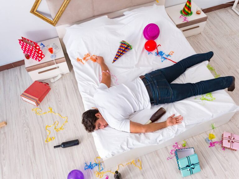 Mężczyzna w ubraniu na łóżku. Obrazek w artykule Odtrucie po alkoholu domowe sposoby. Jak pozbyć się kaca w domowym zaciszu?